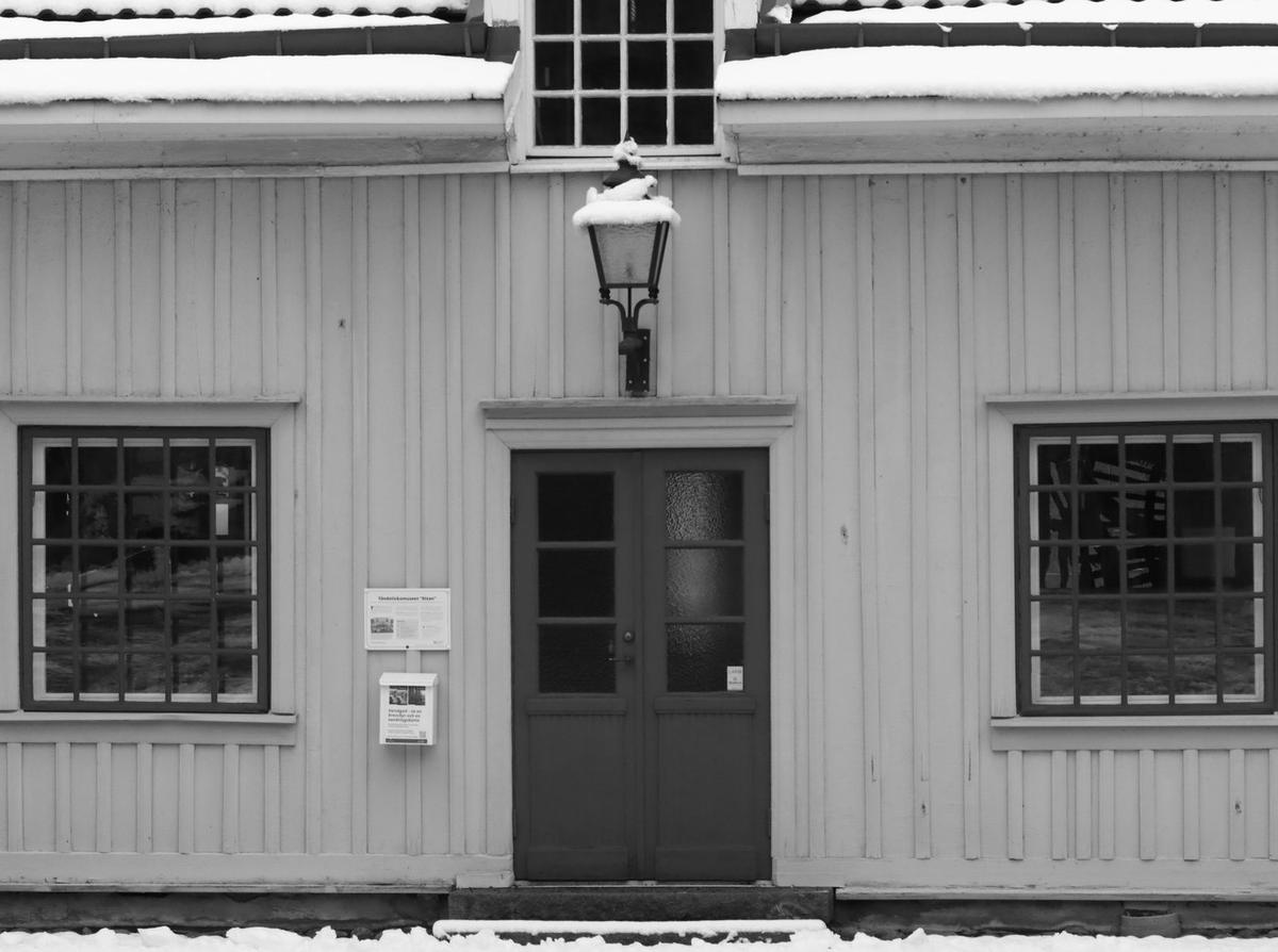 Inngangsparti på et gammelt trehus med røde dører i snø